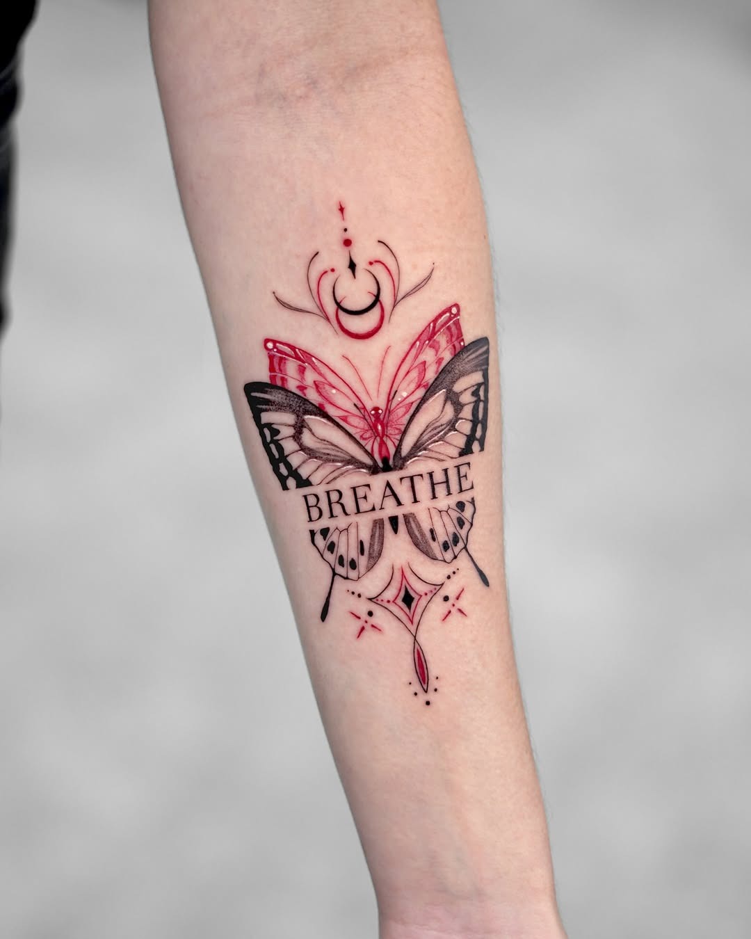 This stunning butterfly tattoo features intricate black and red designs.