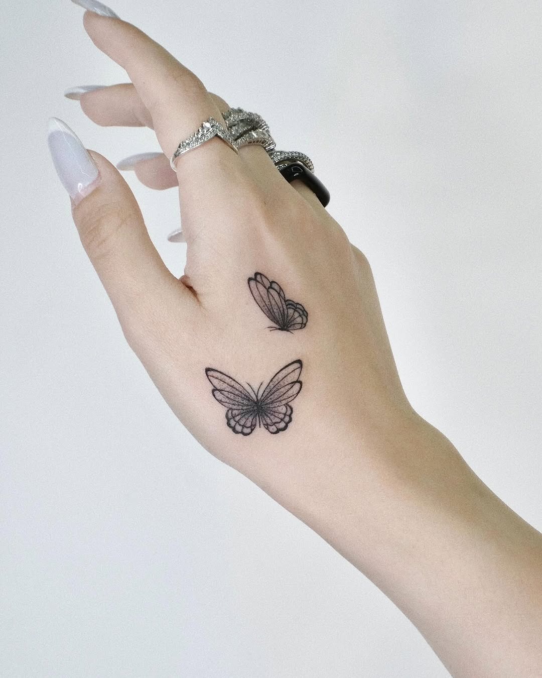 This image showcases delicate butterfly tattoos gracing the hand, embodying elegance and femininity.
