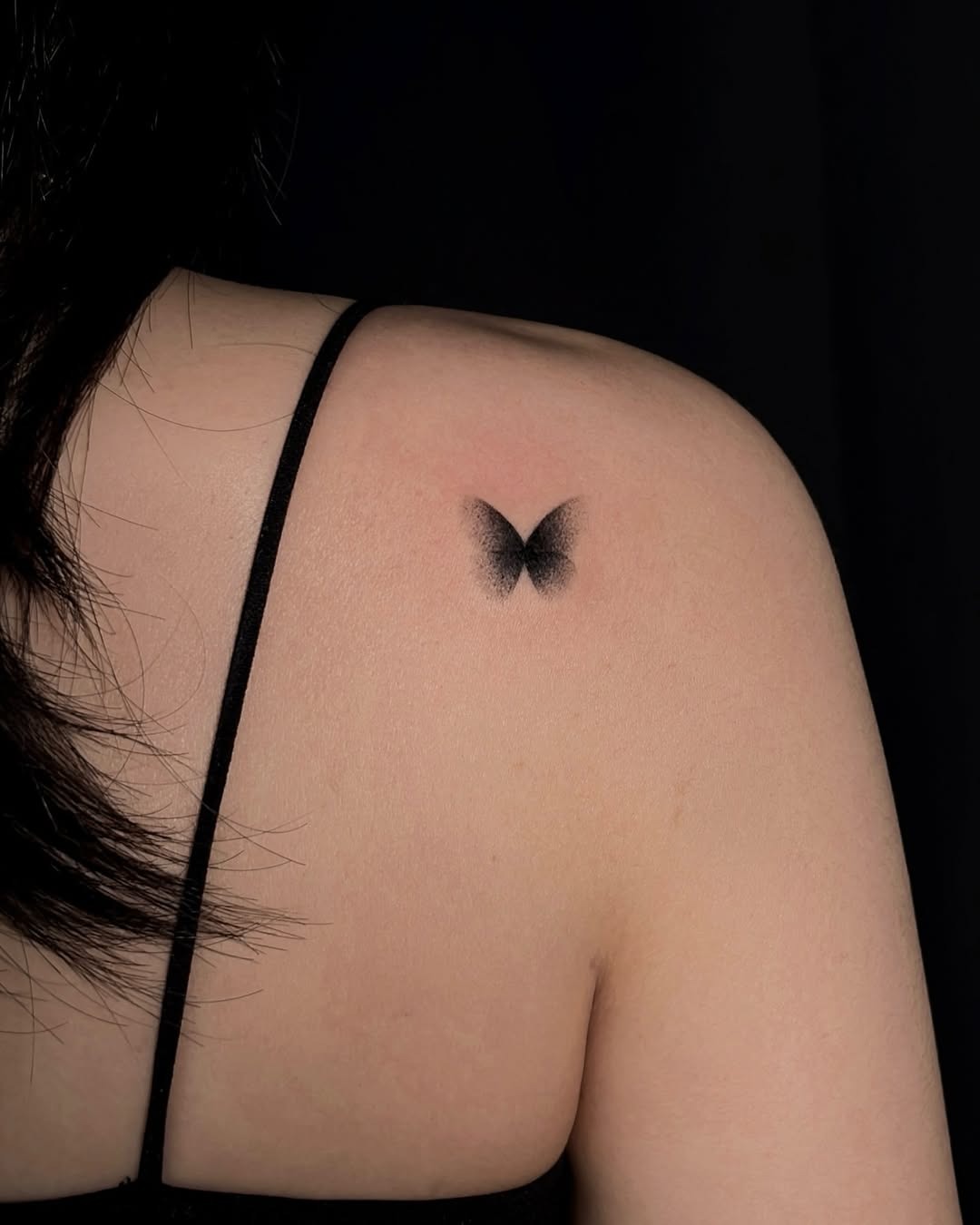 This minimalist butterfly tattoo features soft shading, creating a delicate and ethereal vibe.