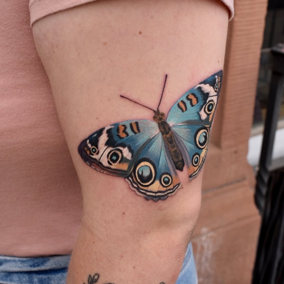 This stunning butterfly tattoo features shades of blue and intricate detailing.