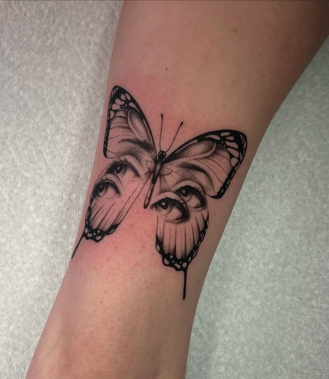 This tattoo features a captivating butterfly design that cleverly incorporates eyes within its wings.
