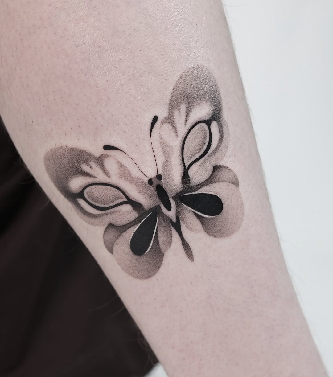 This elegant butterfly tattoo features soft black and gray shading, creating a dreamy effect.