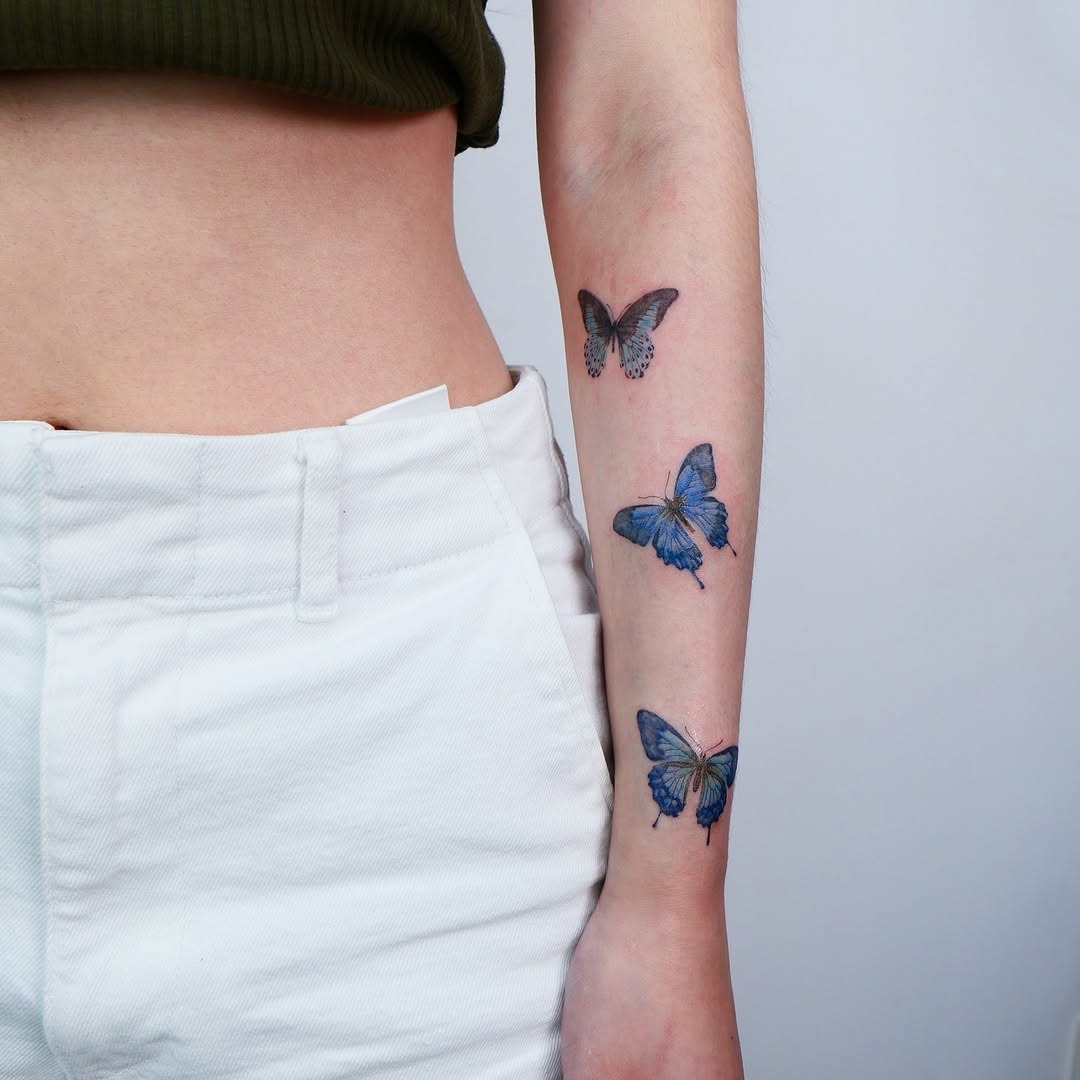 This image showcases a collection of butterfly tattoos elegantly placed on the forearm.