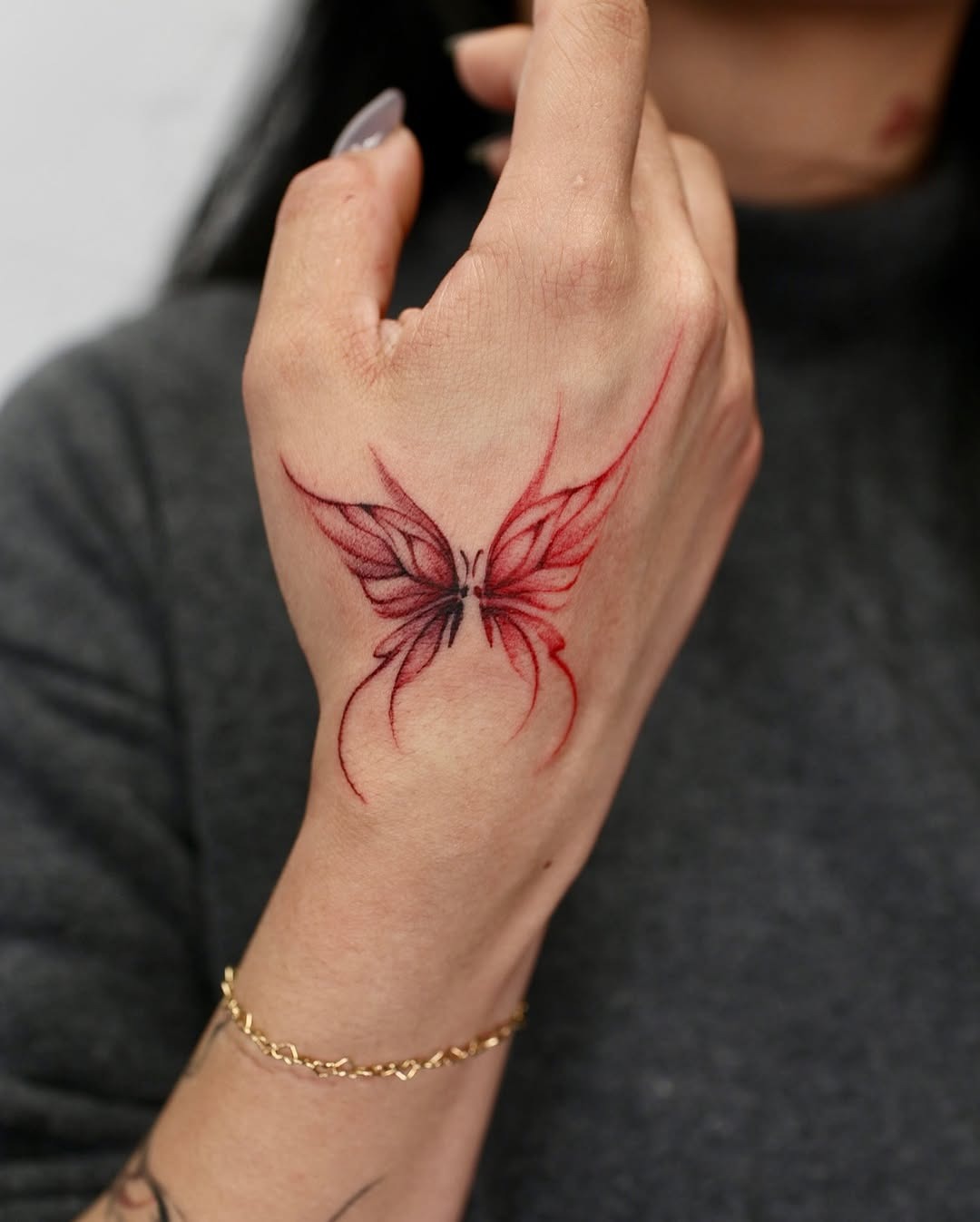 This hand tattoo features a striking red butterfly design, beautifully inked to capture attention.