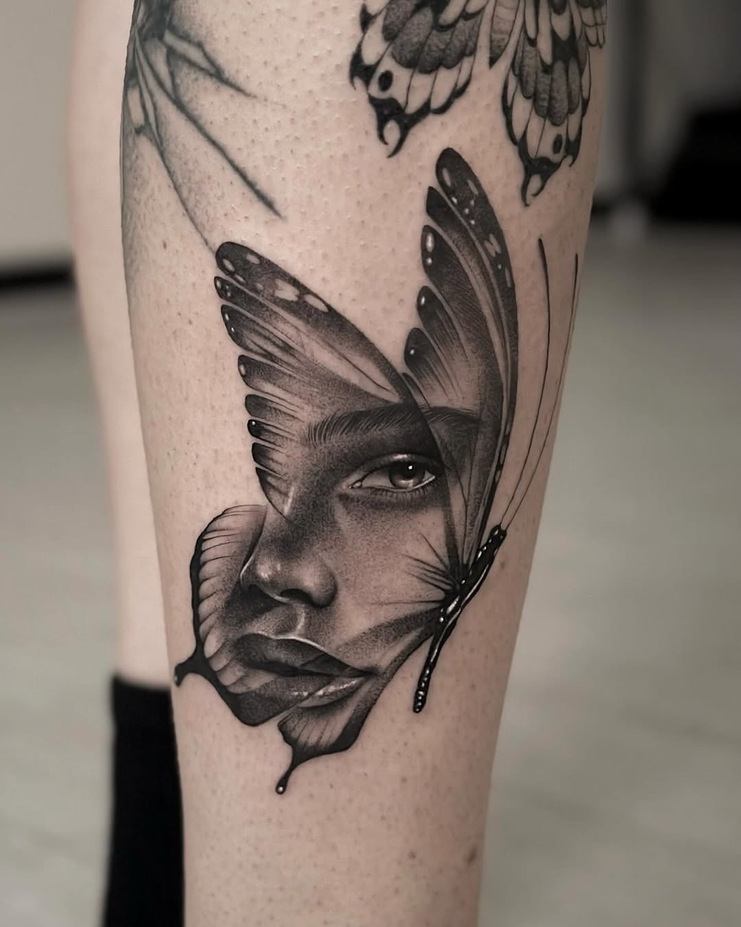 This stunning tattoo blends a butterfly and a face, creating a captivating visual.