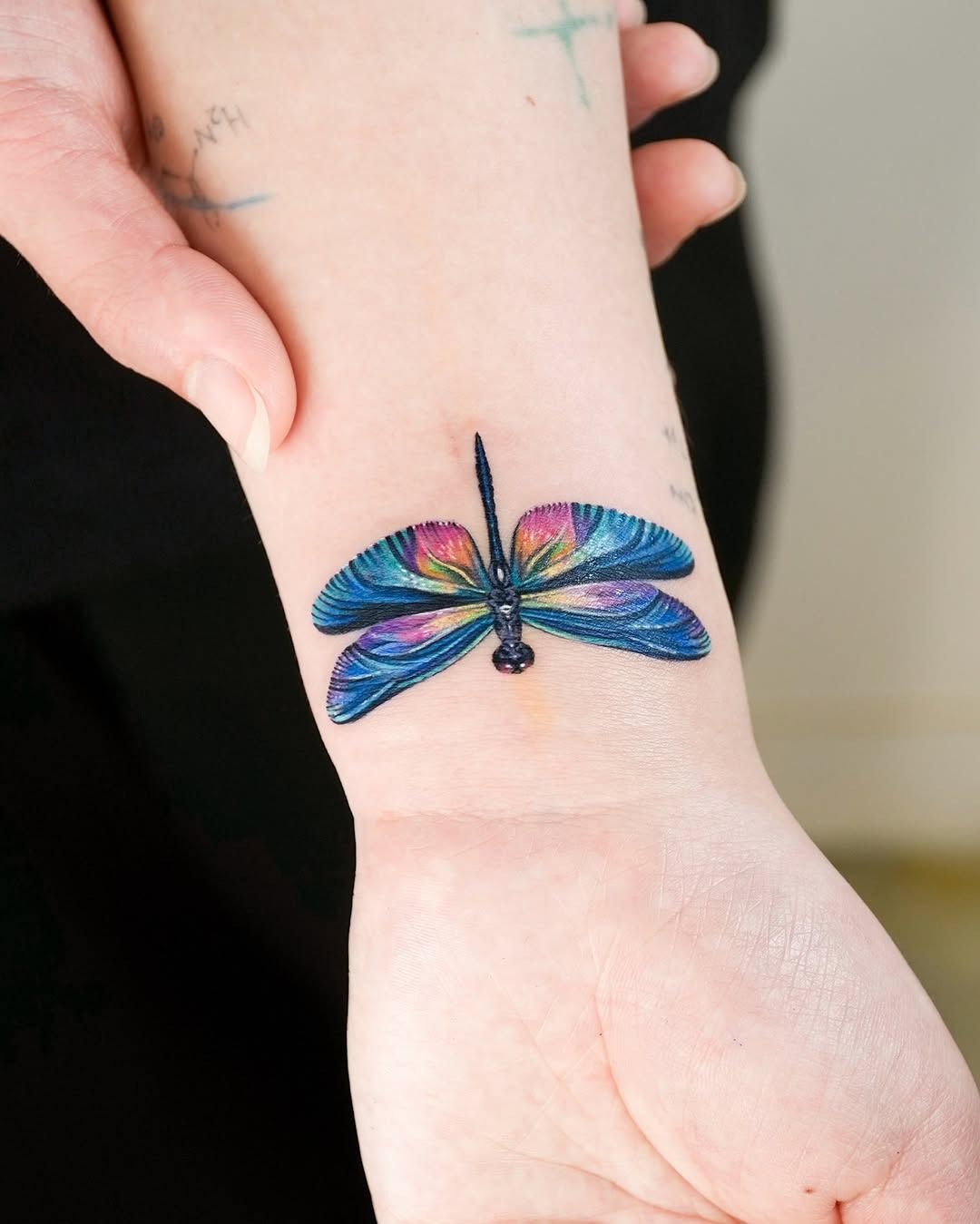 This stunning butterfly tattoo features a palette, showing blues, greens, and hints of pink.