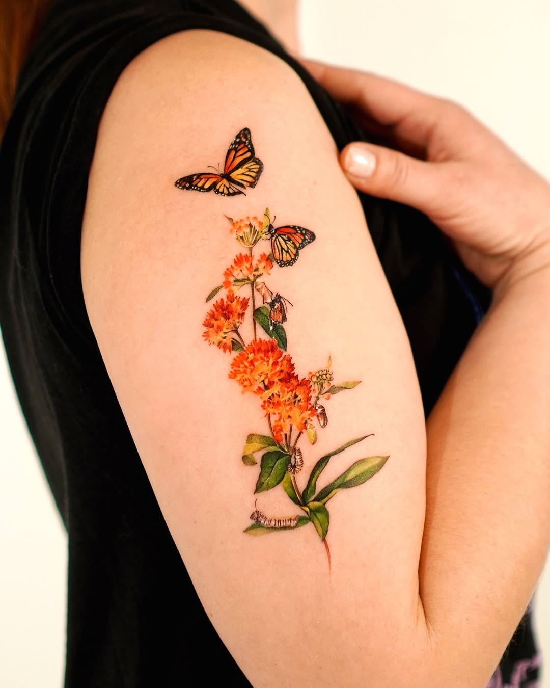 This stunning tattoo features a realistic butterfly perched atop flowers, creating a captivating design.