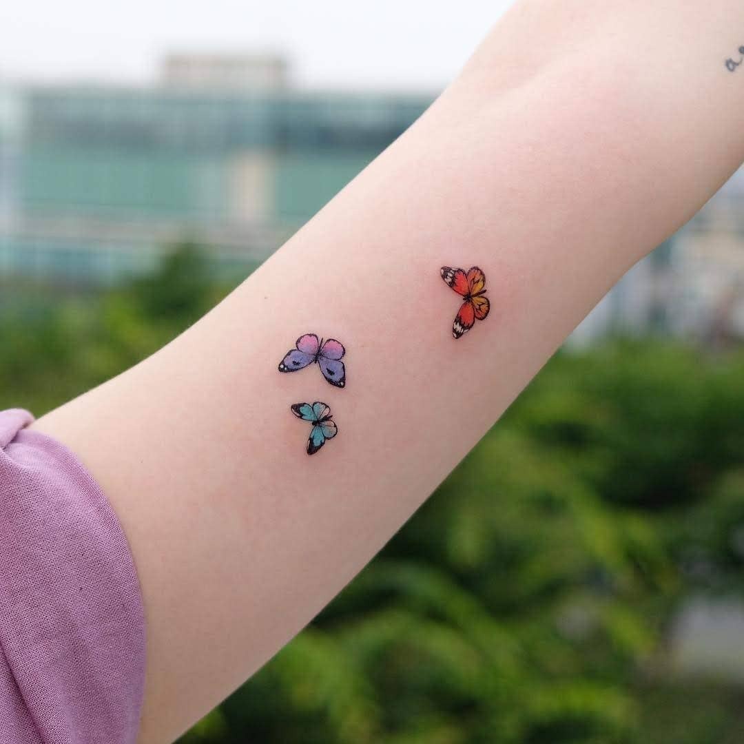 This image showcases three butterfly tattoos on a person's forearm.