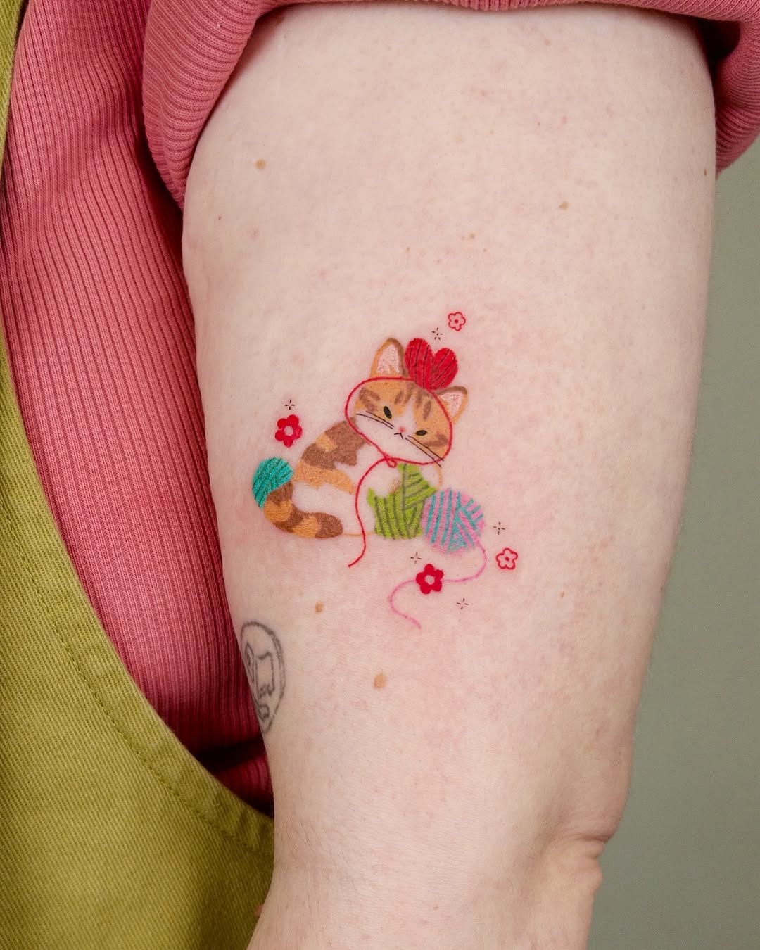 Playful cat tattoo with yarn and flowers Tattoo Design