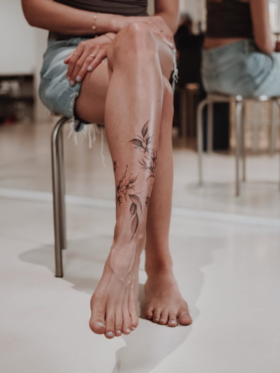 Delicate floral ankle tattoo with leaf accents Tattoo Design
