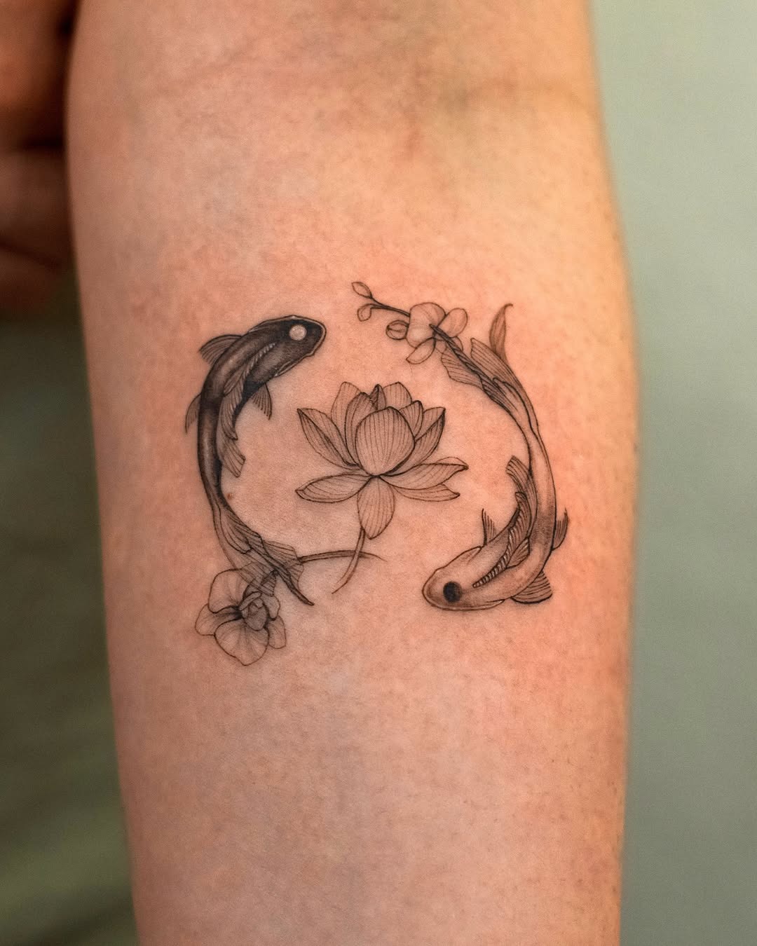 This tattoo features two elegantly intertwined koi fish, symbolizing strength and perseverance.