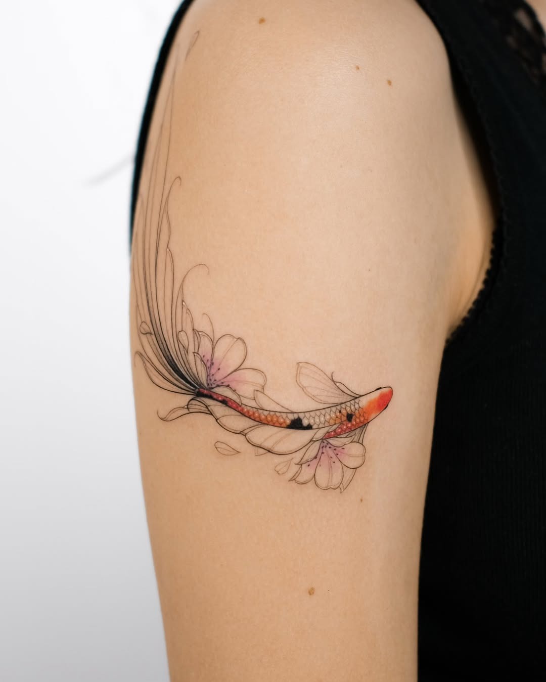 This tattoo features a stunning koi fish that gracefully swims through delicate floral elements.