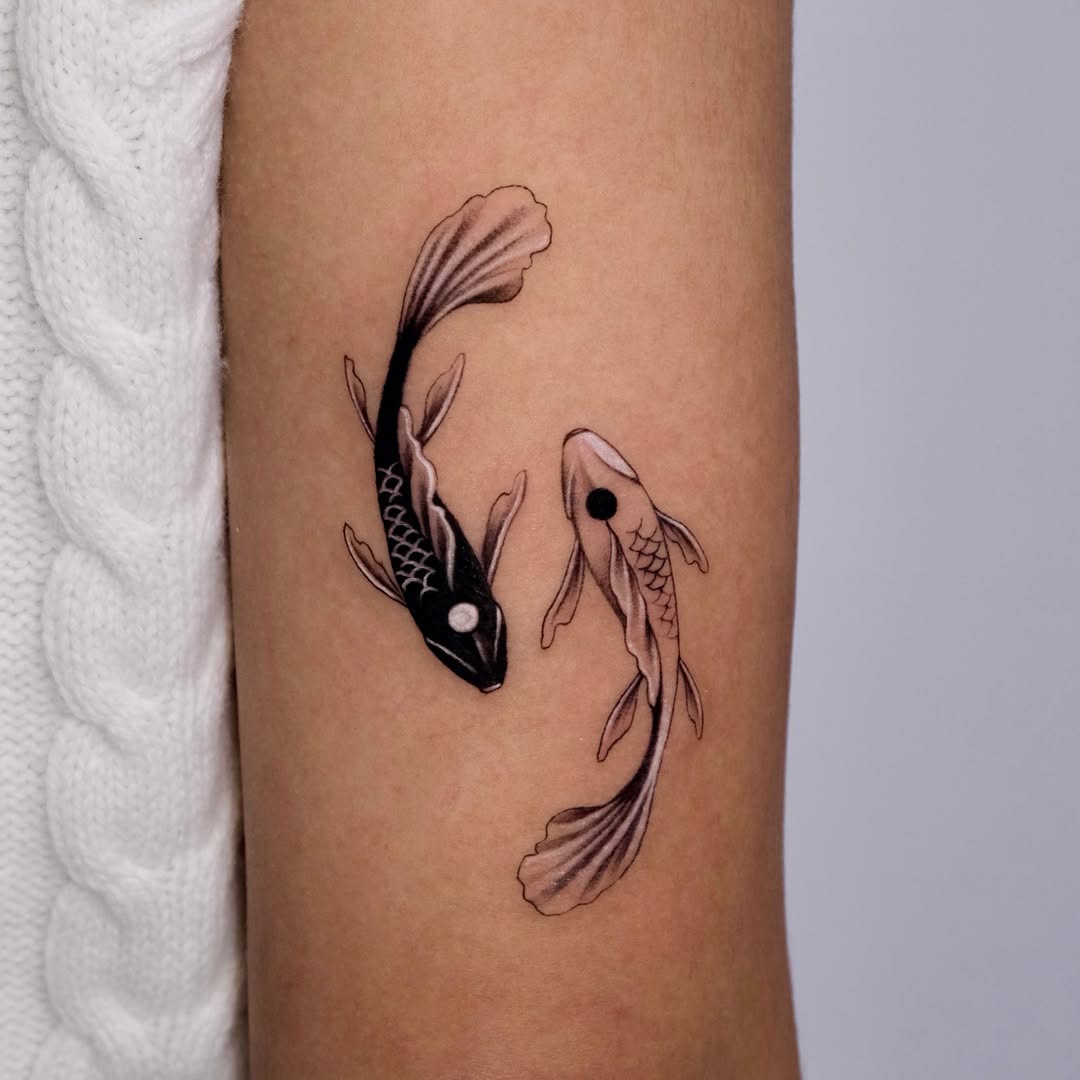 This tattoo features two beautifully designed koi fish, one in black and the other in shades of brown.