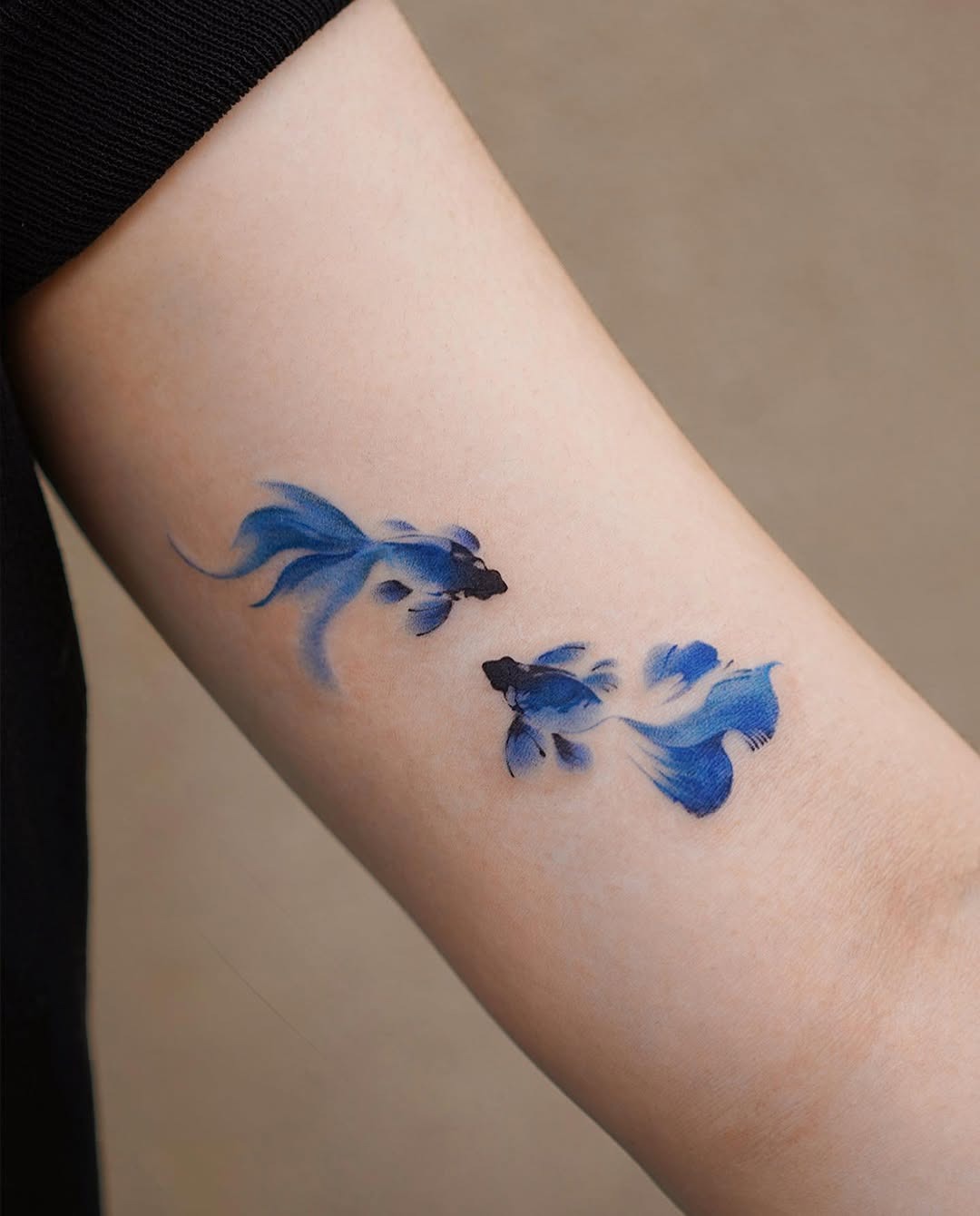 This tattoo features stunning blue koi fish gracefully swimming.