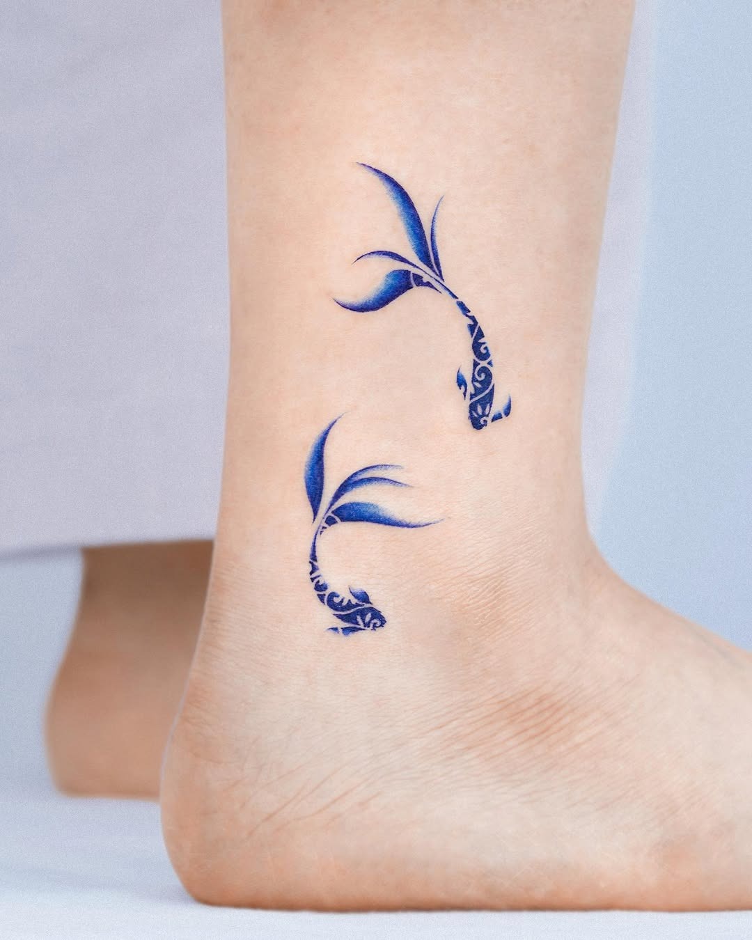 This image features a pair of delicate koi fish tattoos, artistically designed in serene blue tones.