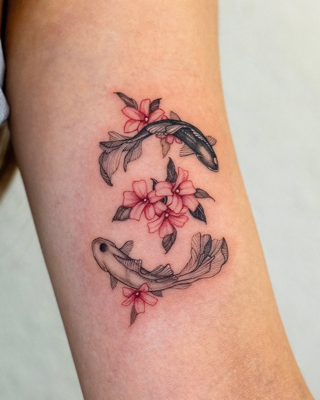 This tattoo showcases two koi fish swimming gracefully around delicate flowers.