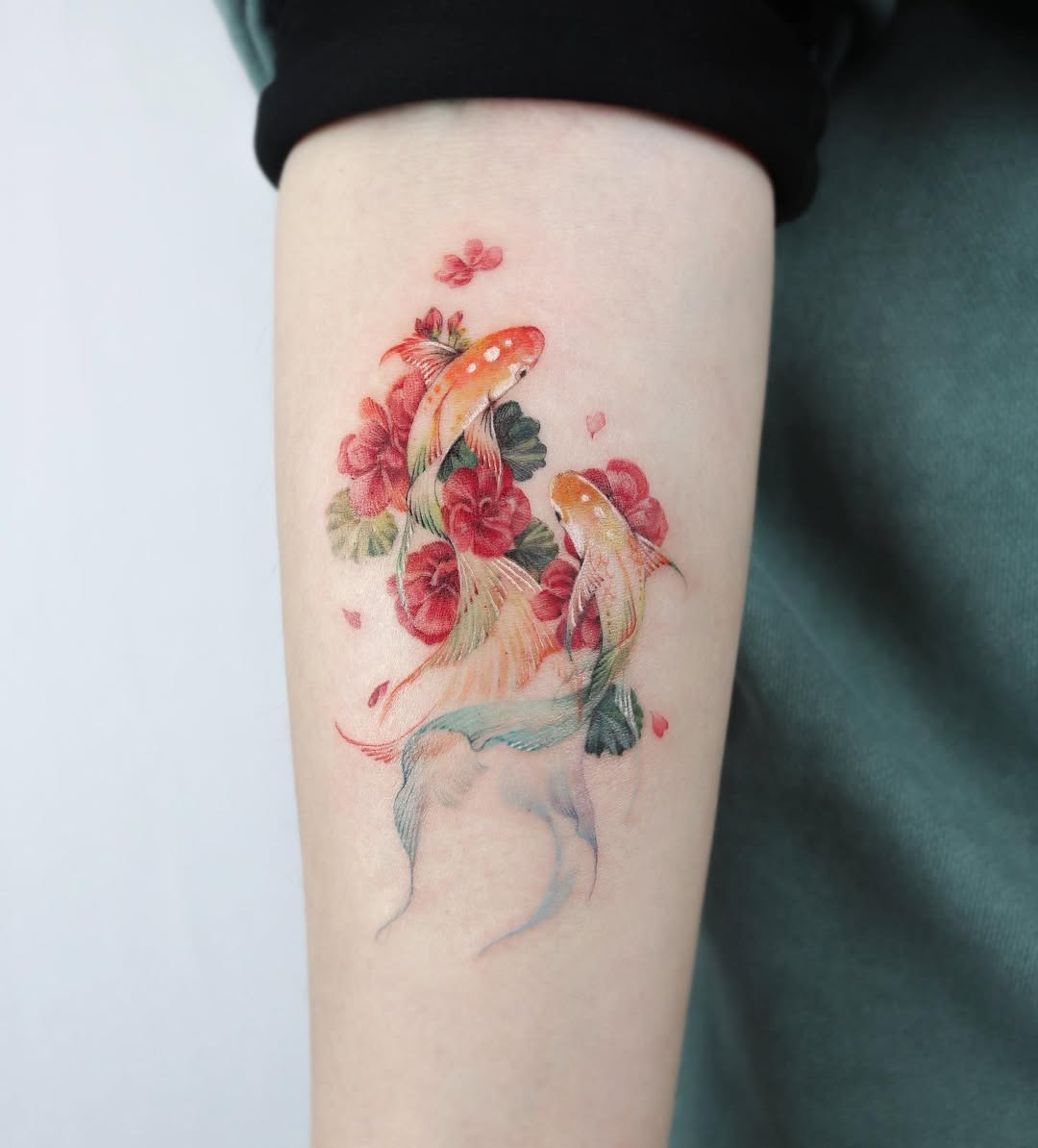 This tattoo showcases two beautifully detailed koi fish swimming among blooming flowers.