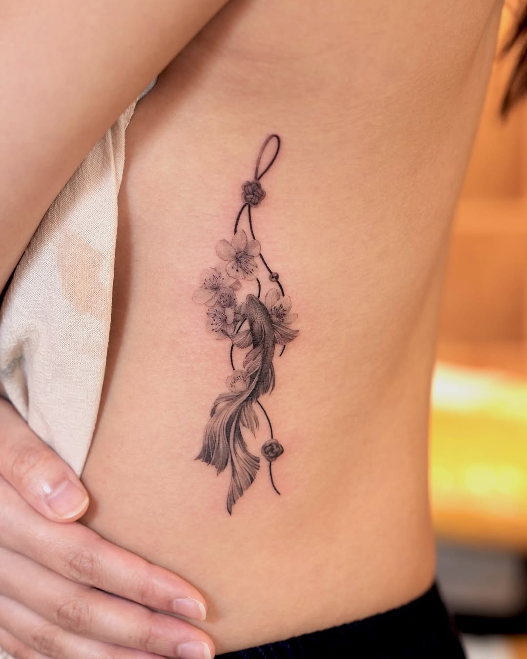 This beautiful tattoo features a koi fish entwined with cherry blossoms, showing intricate details and delicate lines.
