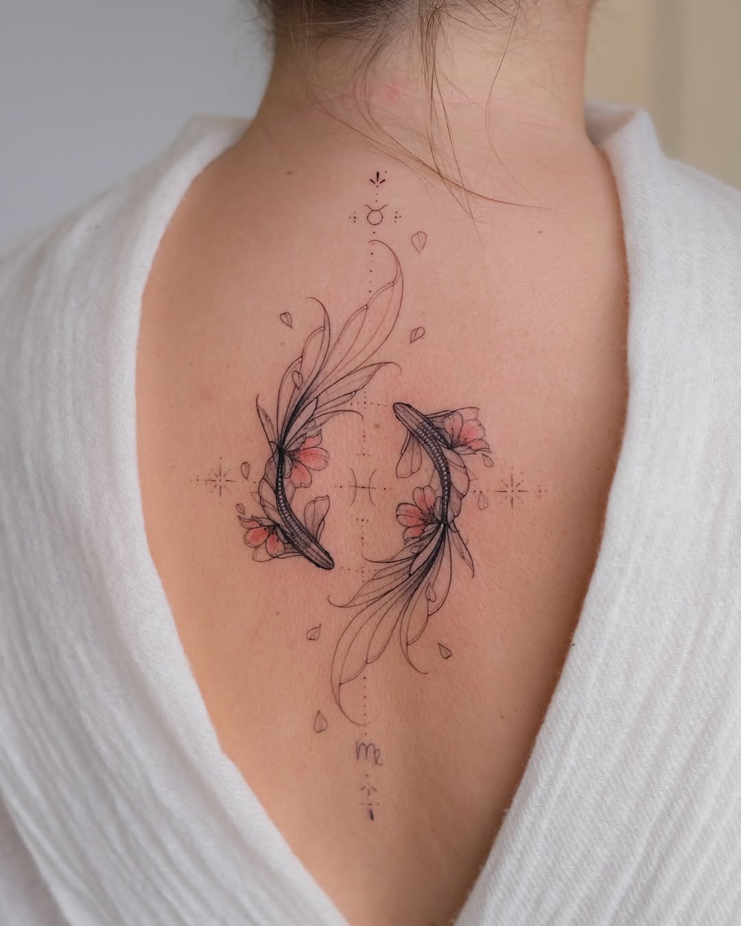 This stunning tattoo showcases two gracefully designed koi fish intertwined with delicate flowers.