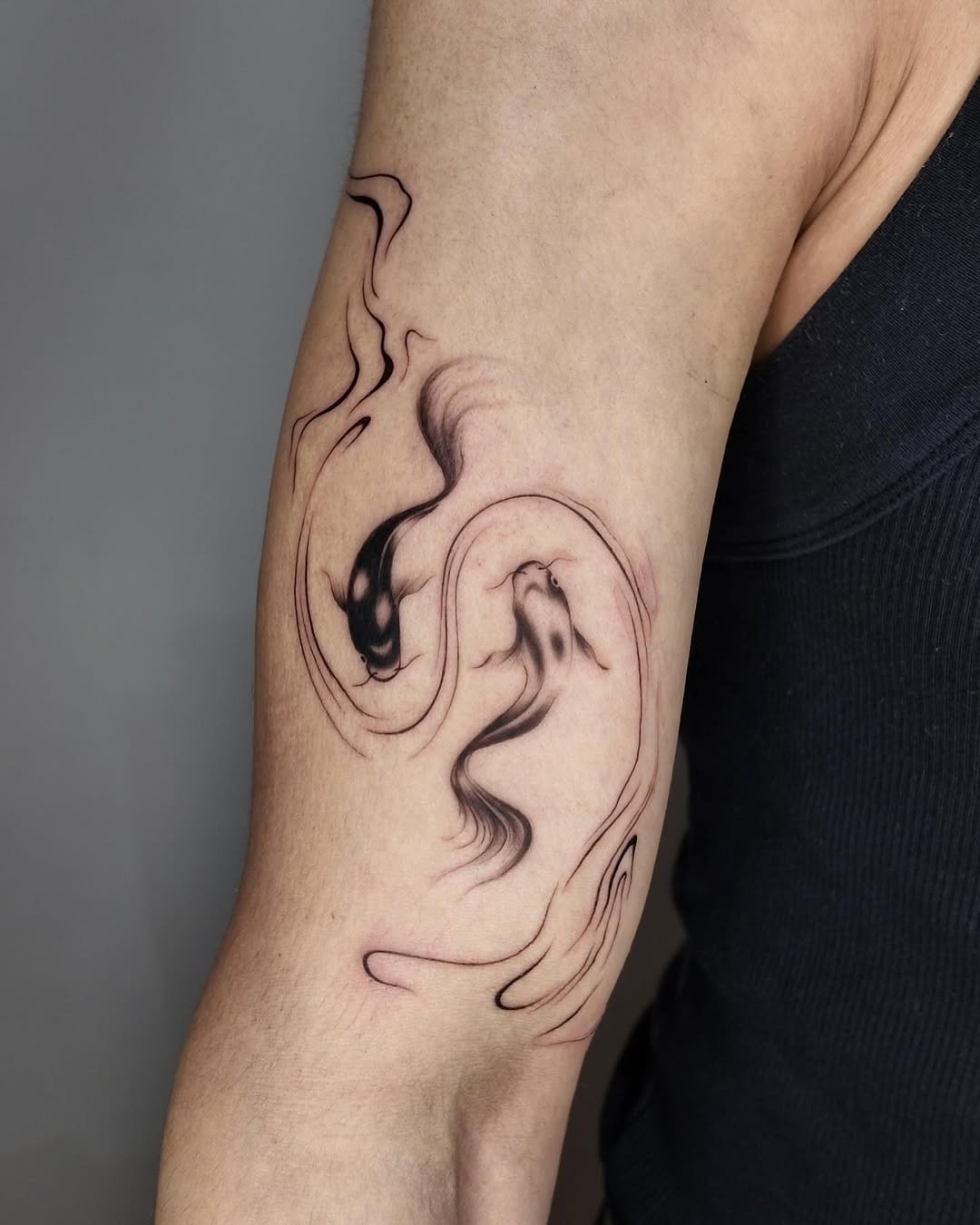 This koi fish tattoo features an elaborate design in black ink, flowing gracefully along the arm.