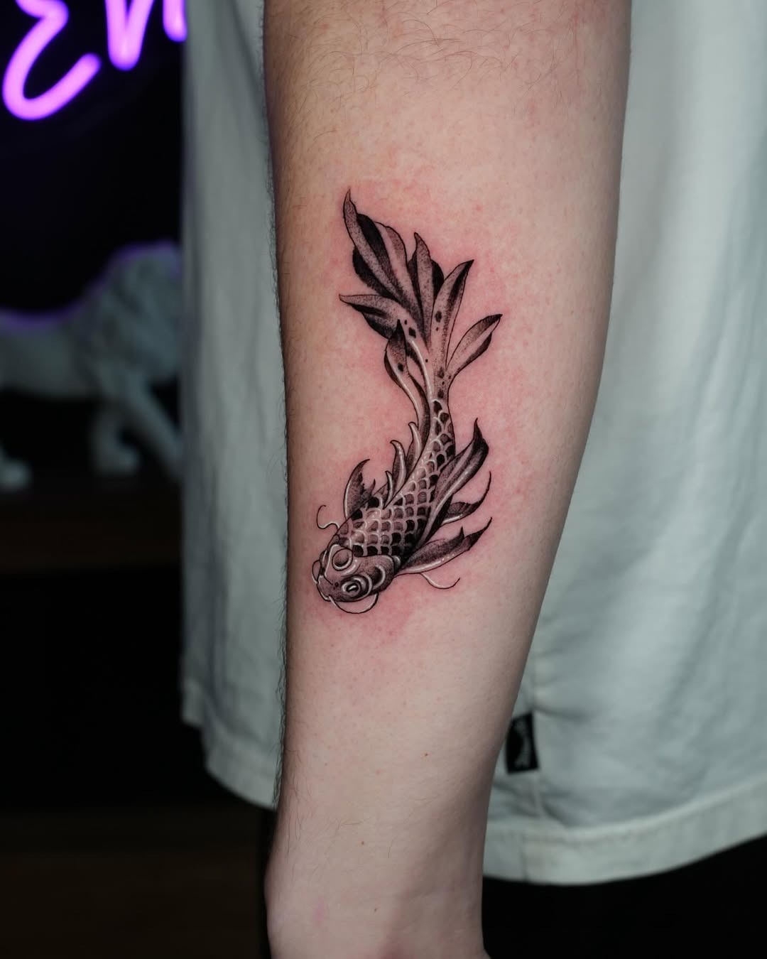 This tattoo features a beautifully designed koi fish entwined in decorative elements.