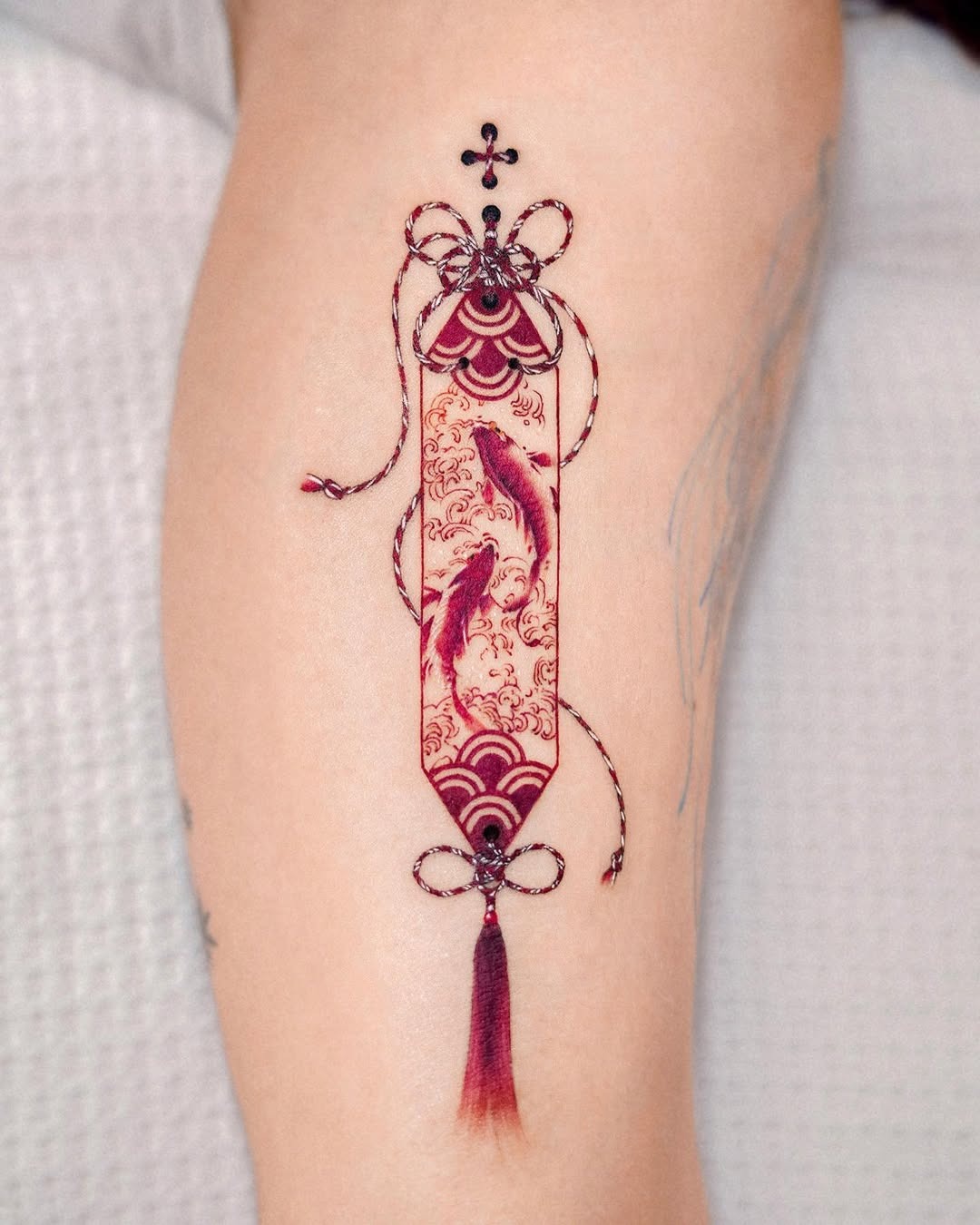 This tattoo features a beautifully designed koi fish entwined in decorative elements.