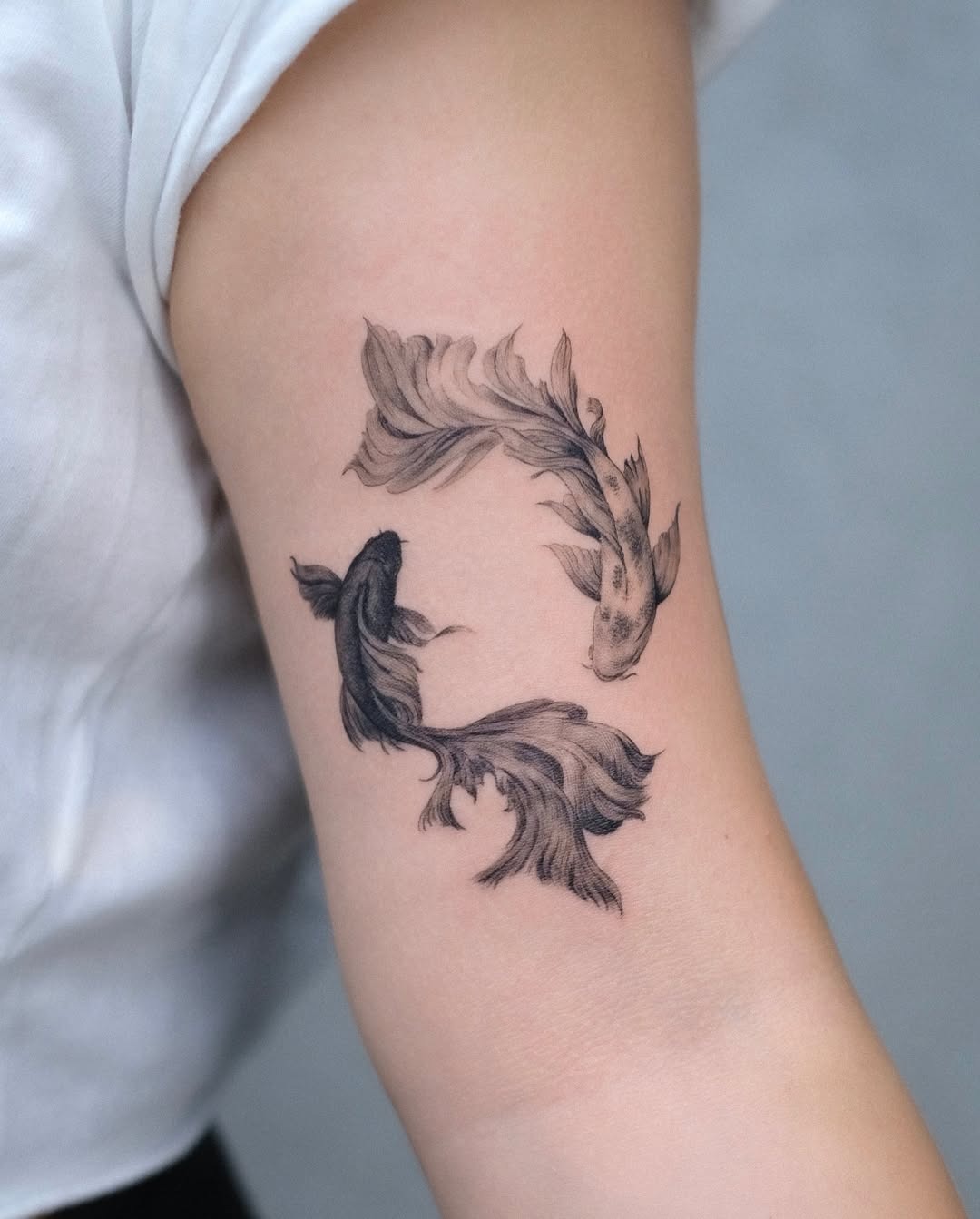 This tattoo features two koi fish swimming in a circular motion, symbolizing harmony and balance.