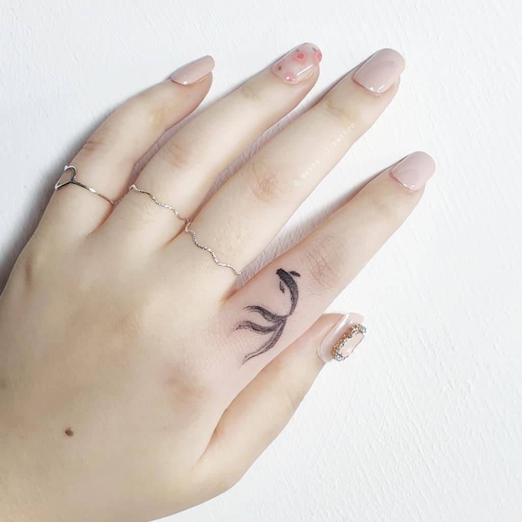 This delicate koi fish tattoo gracefully adorns a hand.