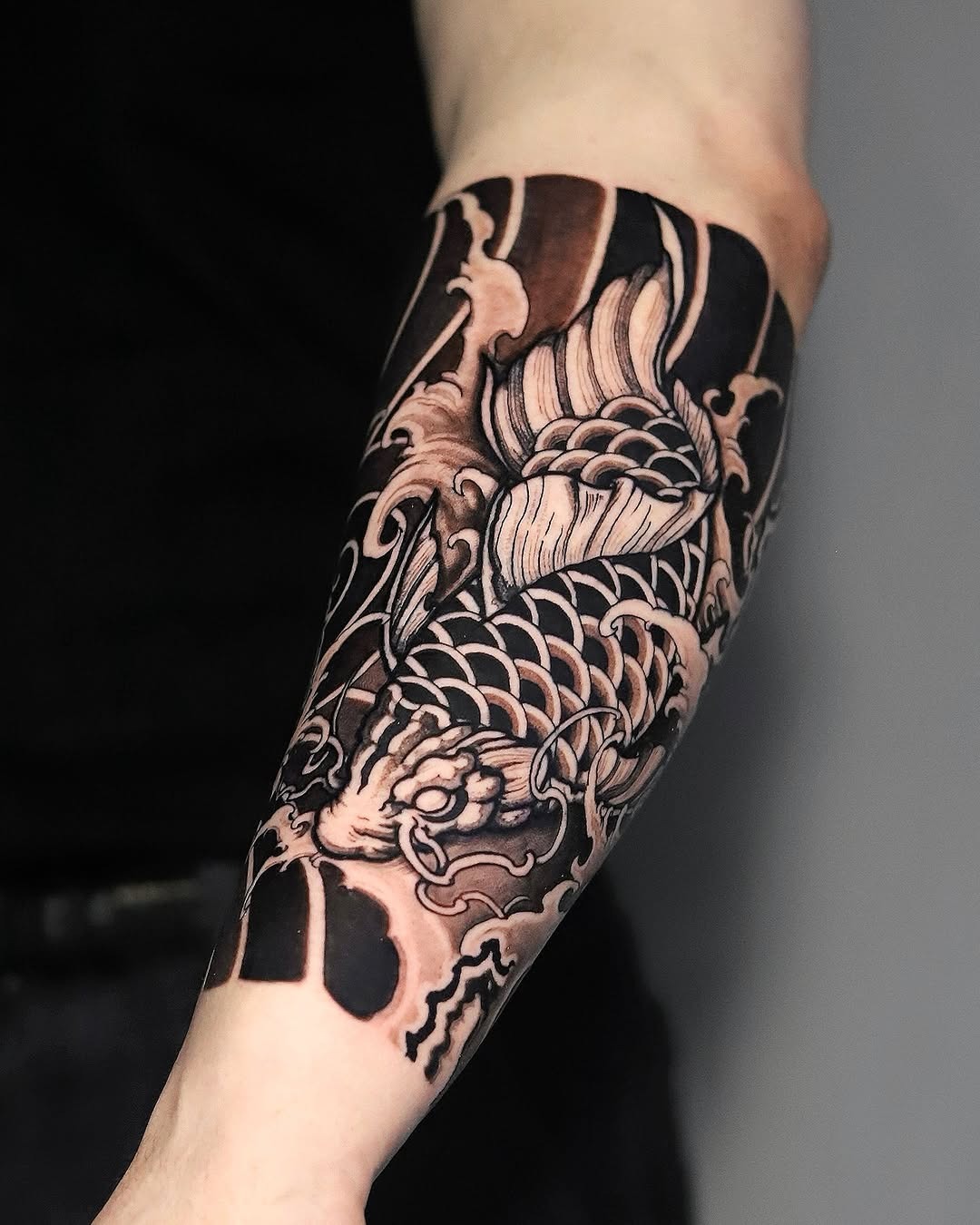 This beautiful koi fish tattoo wraps around the forearm, showing detailed line work and a striking design.