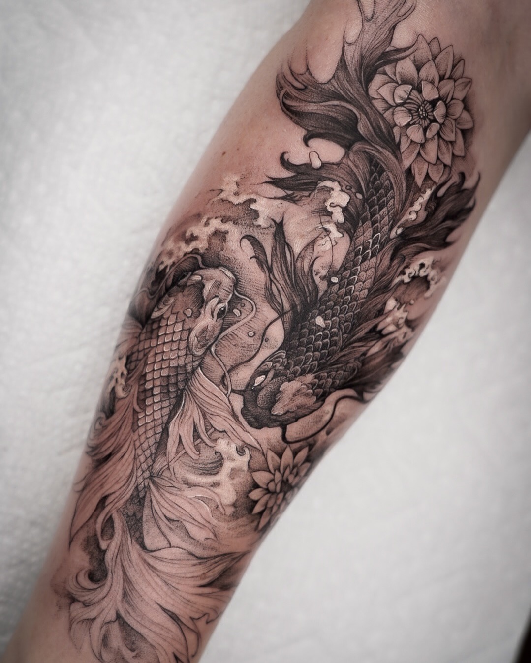 This stunning tattoo features a beautifully detailed koi fish entwined with flowing waves and delicate flowers.