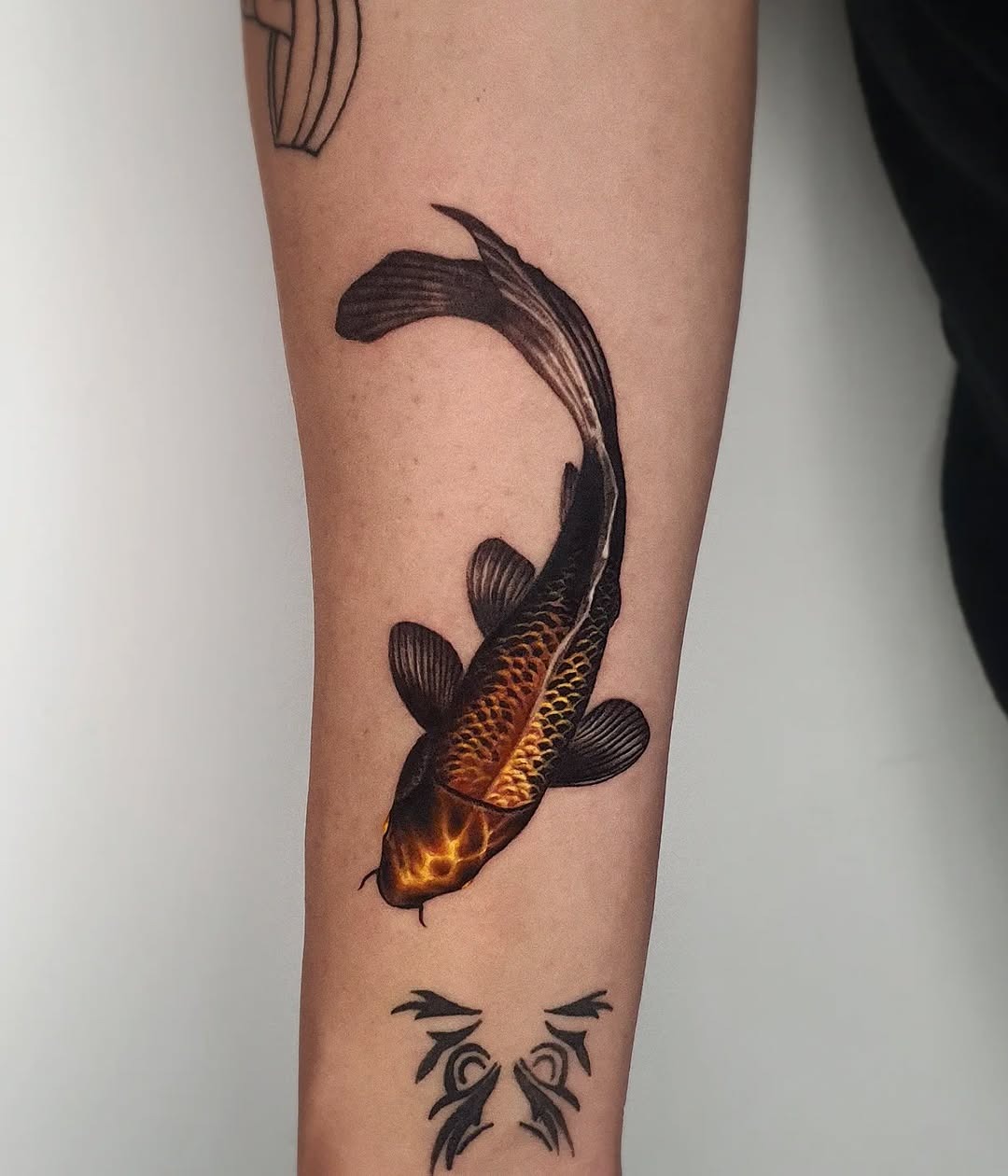 This tattoo showcases a beautifully detailed koi fish swimming elegantly along the arm.
