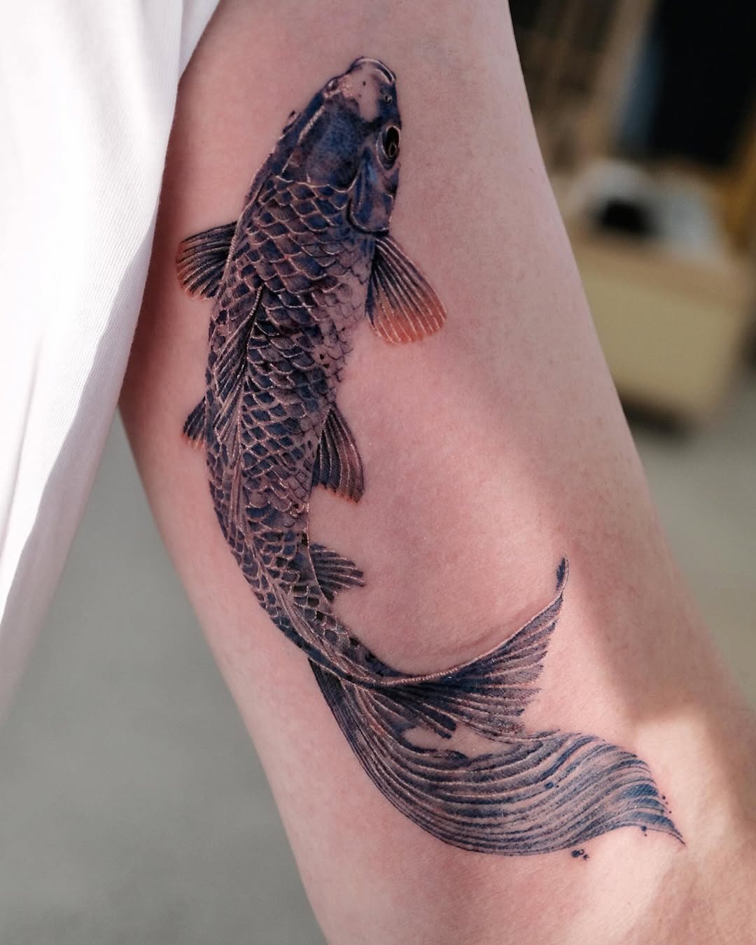 This tattoo features a beautifully realistic koi fish with intricate scales and colors.
