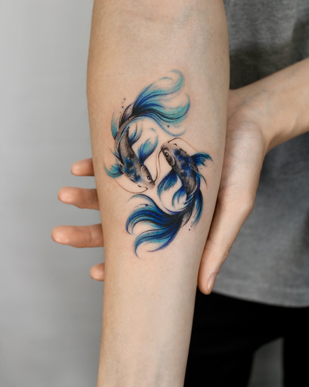 This tattoo showcases two koi fish in a graceful swirl, highlighted with stunning blue colors.