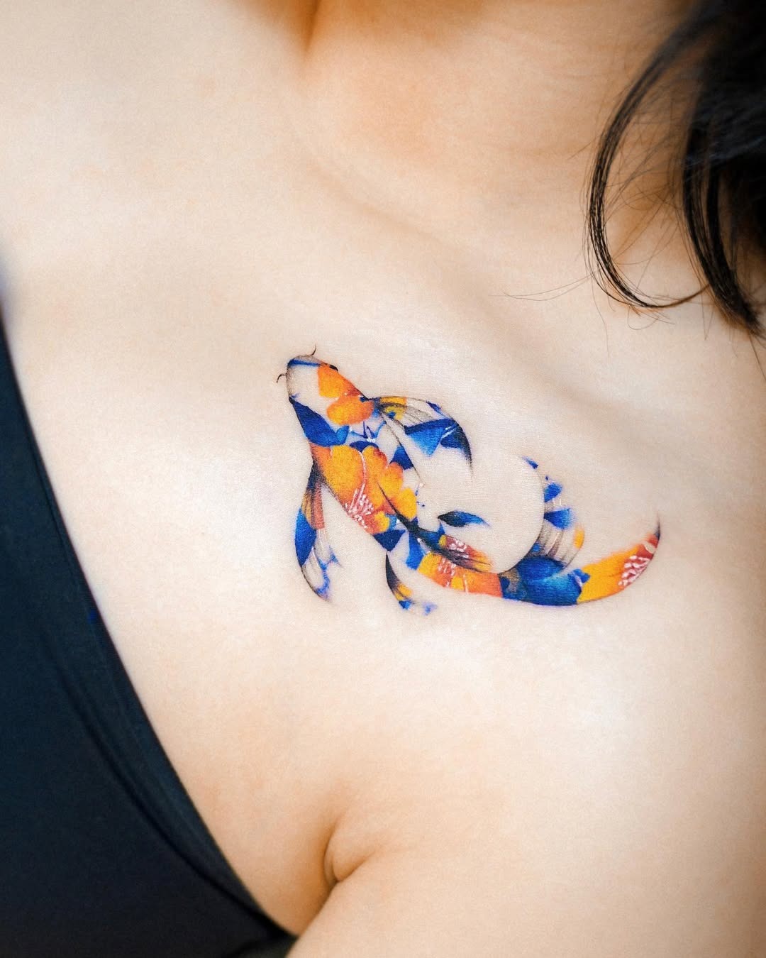 This tattoo features a vivid koi fish intertwined with floral patterns, showing an artistic blend of color and design.