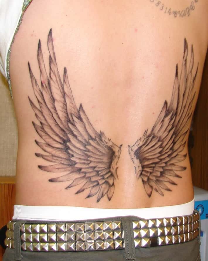 This striking design features large, intricately shaded angel wings spanning the lower back.