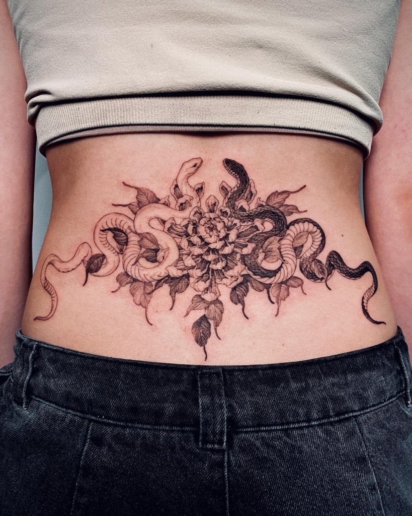 For those seeking a bold statement, this tattoo blends ornamental floral patterns with intertwining snakes, creating an otherworldly effect.