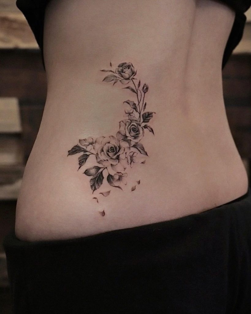 A beautifully asymmetrical floral tattoo wraps around the side of the lower back.