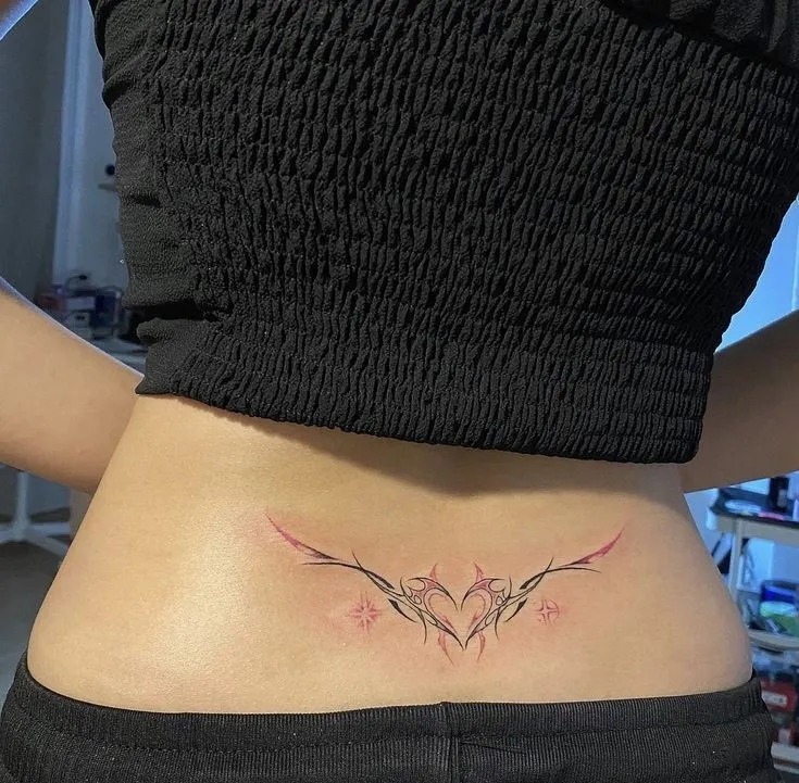 This elegant tattoo is a delicate blend of thin black lines forming a heart-centered design.