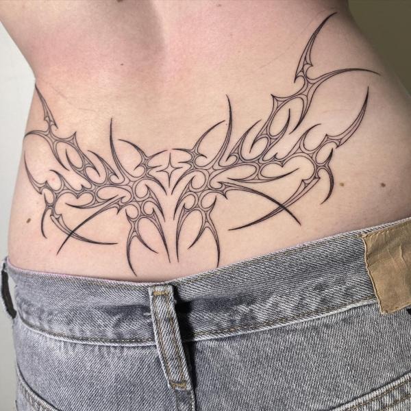 This intricate tribal tattoo showcases an abstract design with sharp points and smooth curves, forming a symmetrical and visually dynamic composition.