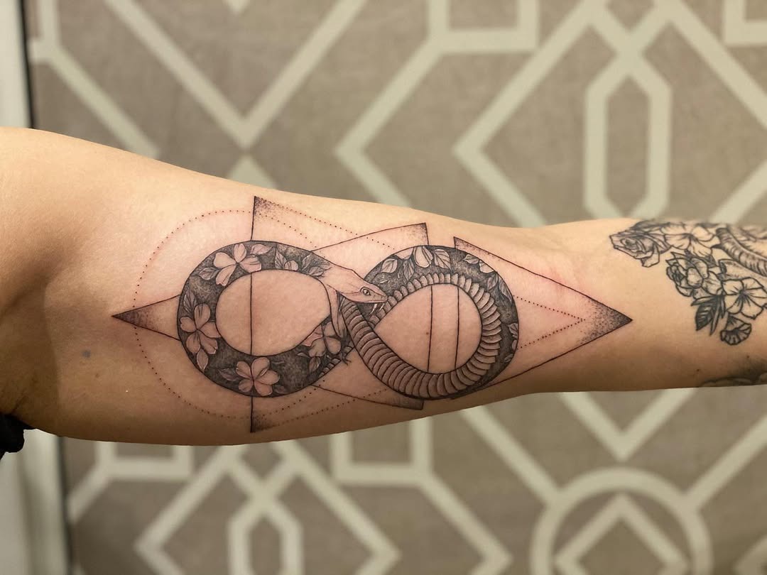 Elegant ouroboros tattoo with floral infinity design Tattoo Design