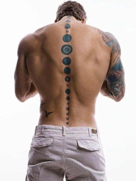 Like moon phases drawn in slow motion, this full-spine tattoo uses dark blue ink and circular gradients to depict planetary cycles.