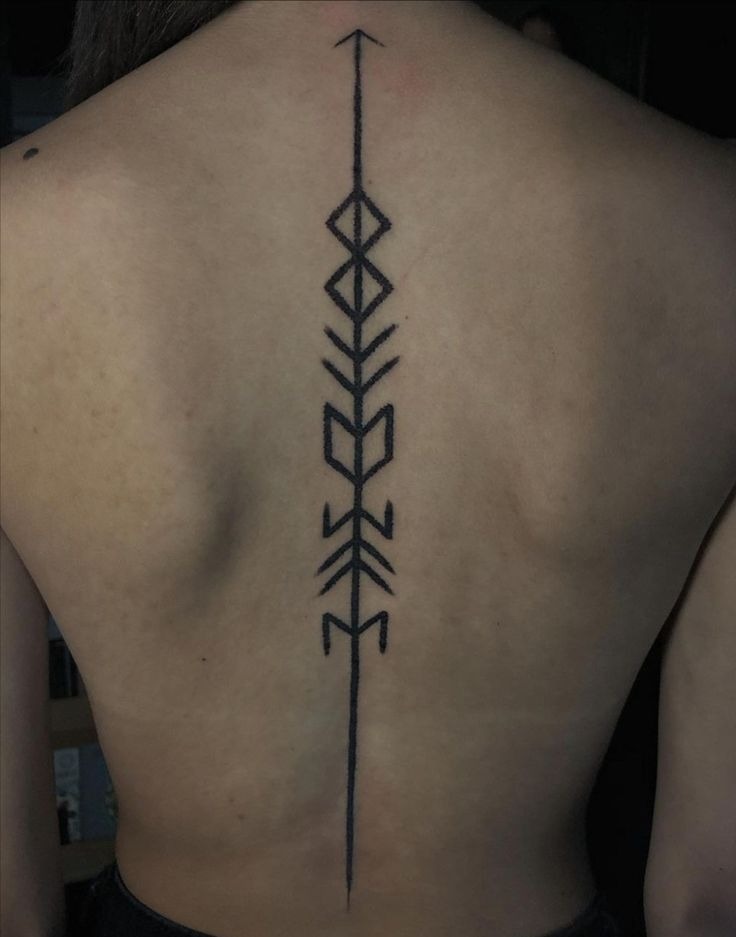 Clean and linear, this arrow-shaped tattoo evokes ancient runes or text-inspired designs.