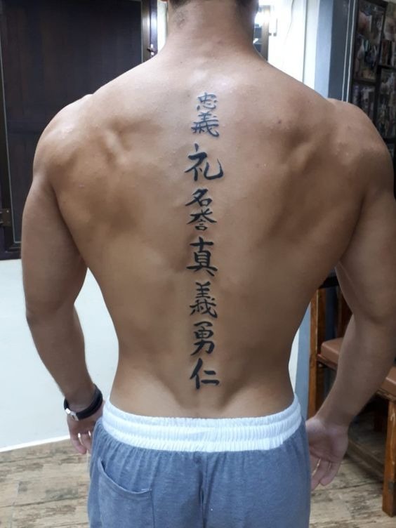 This vertical text tattoo, composed of traditional Kanji characters, anchors the spine with bold, confident strokes.
