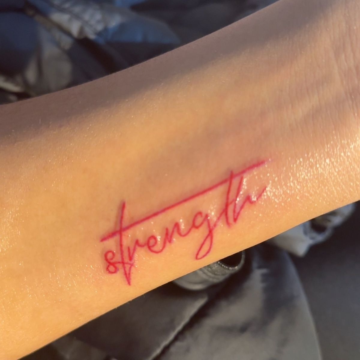 Bold Red Ink Strength Statement, a tattoo design rendered in bold traditional for the arm.
