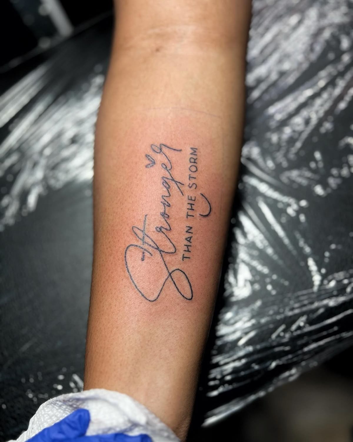 Stronger Than the Storm Script Tattoo, a tattoo design rendered in clean detailed linework for the forearm.