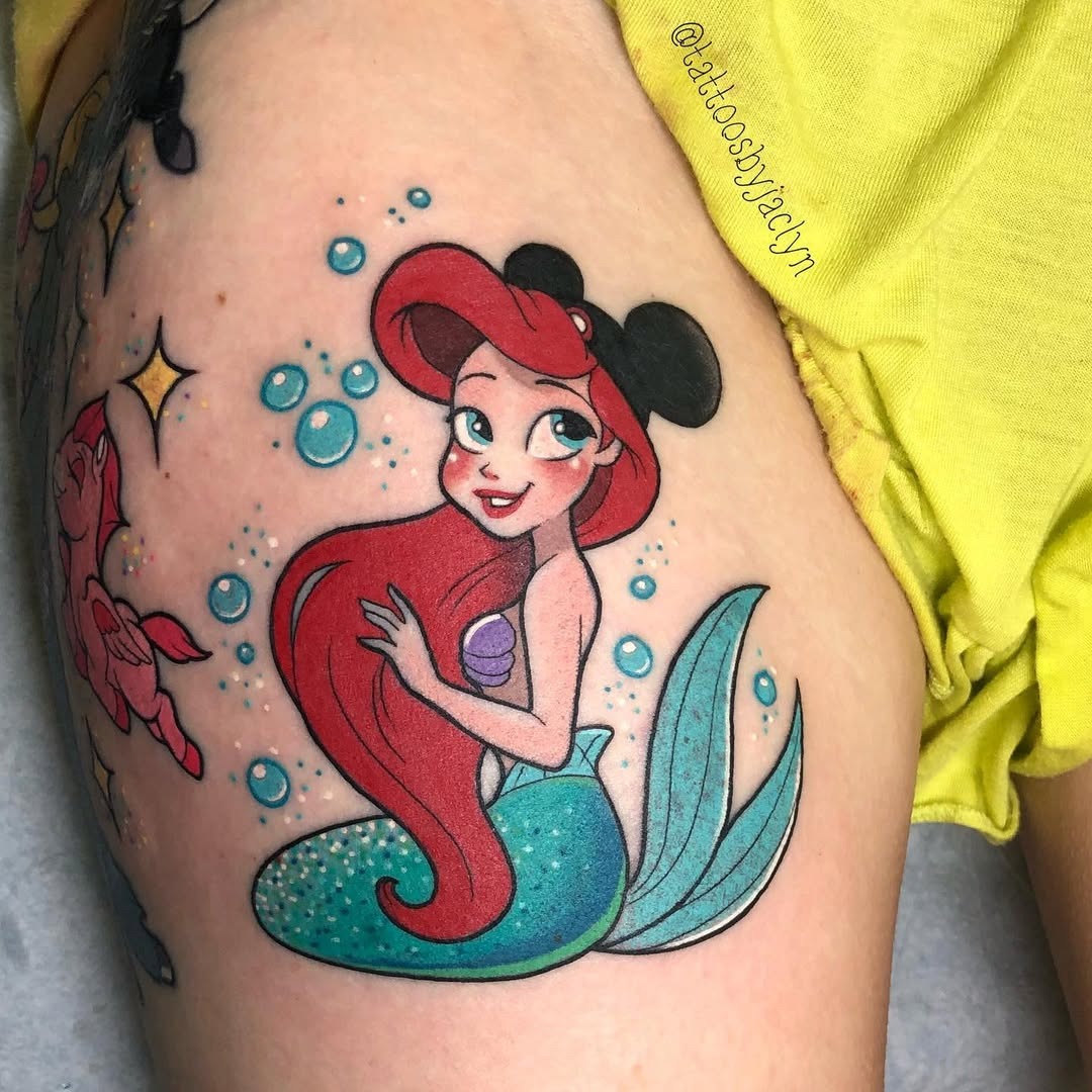 This tattoo features Ariel, the beloved mermaid, radiating charm.