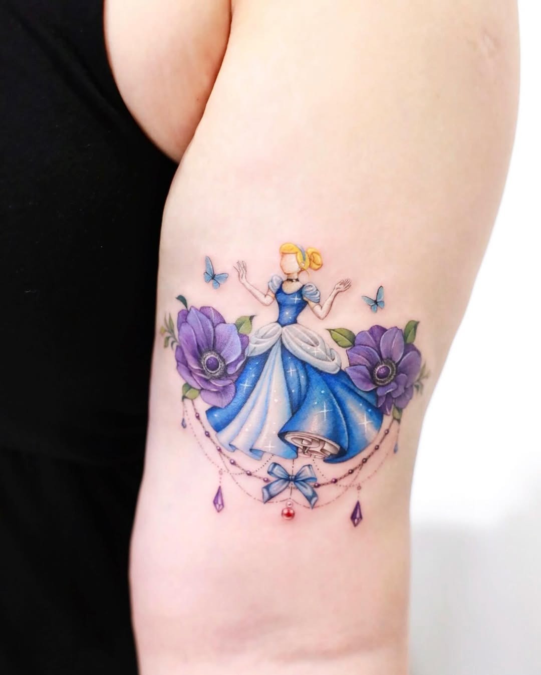 This delightful tattoo showcases Cinderella amid purple flowers, capturing her enchanting essence.