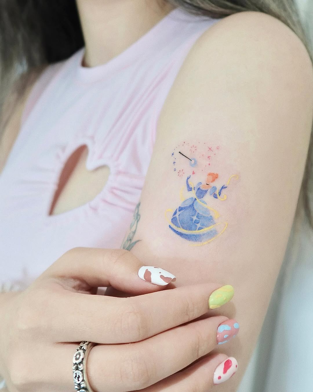 This tattoo features Cinderella in her iconic blue gown, surrounded by whimsical sparkles.