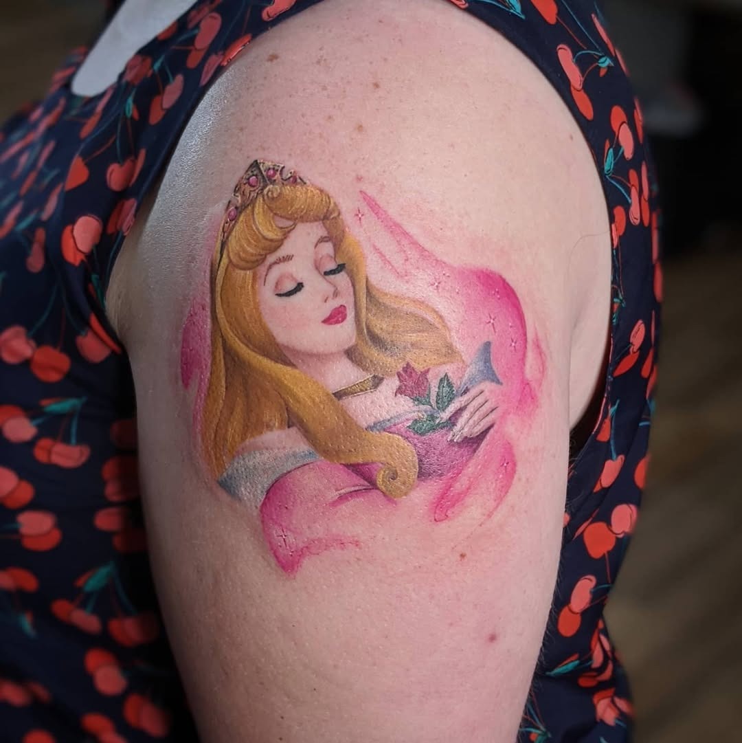 This stunning tattoo features Princess Aurora nestled in a swirl of pink hues, radiating elegance and charm.