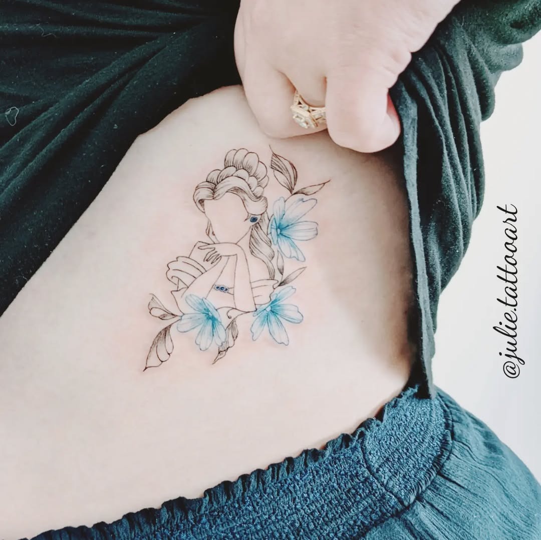 This beautiful tattoo features Belle from Disney's 'Beauty and the Beast' amidst delicate blue flowers.